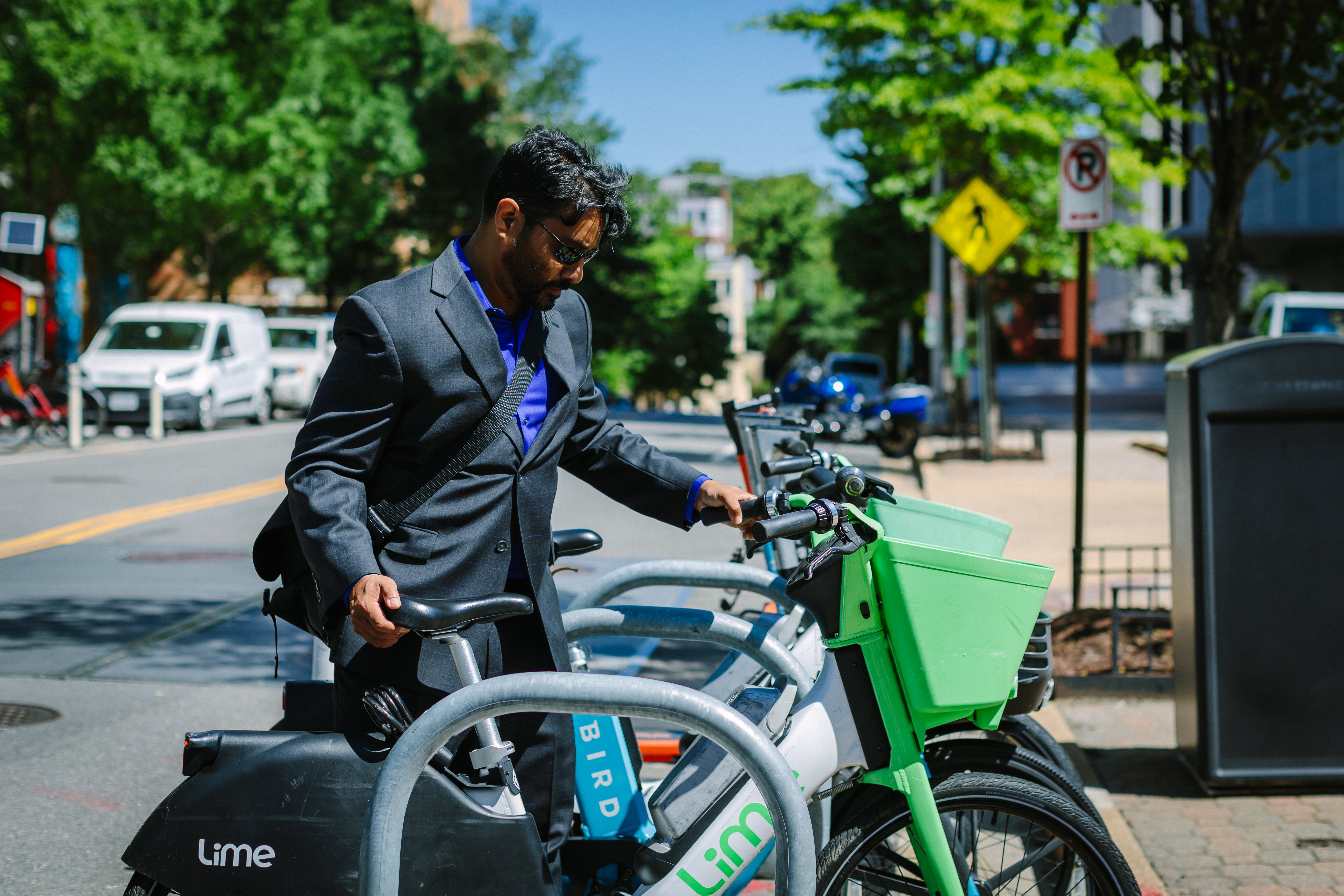 Image of man in a grey suit placing his bike on a rack
